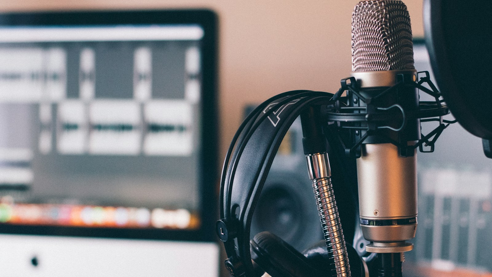 Voice UX designer creative workspace with a studio microphone, tablet displaying speech synthesis audio waveform, and dialogue conversation flow diagrams on paper.