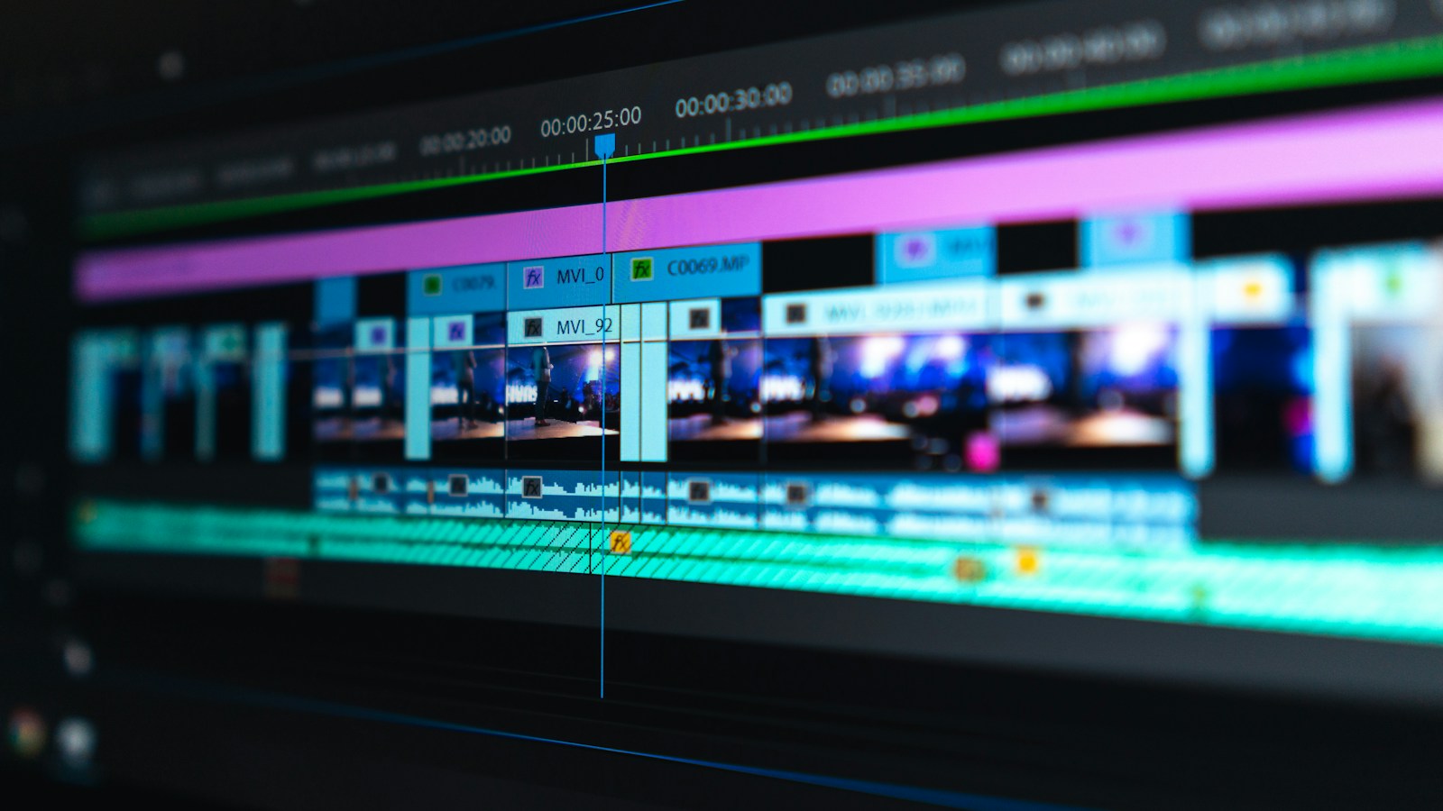 Video creator desktop editing setup with a smartphone mounted in vertical orientation showing a dynamic 3-second hook, backed by a monitor with video timeline waveforms and captions.